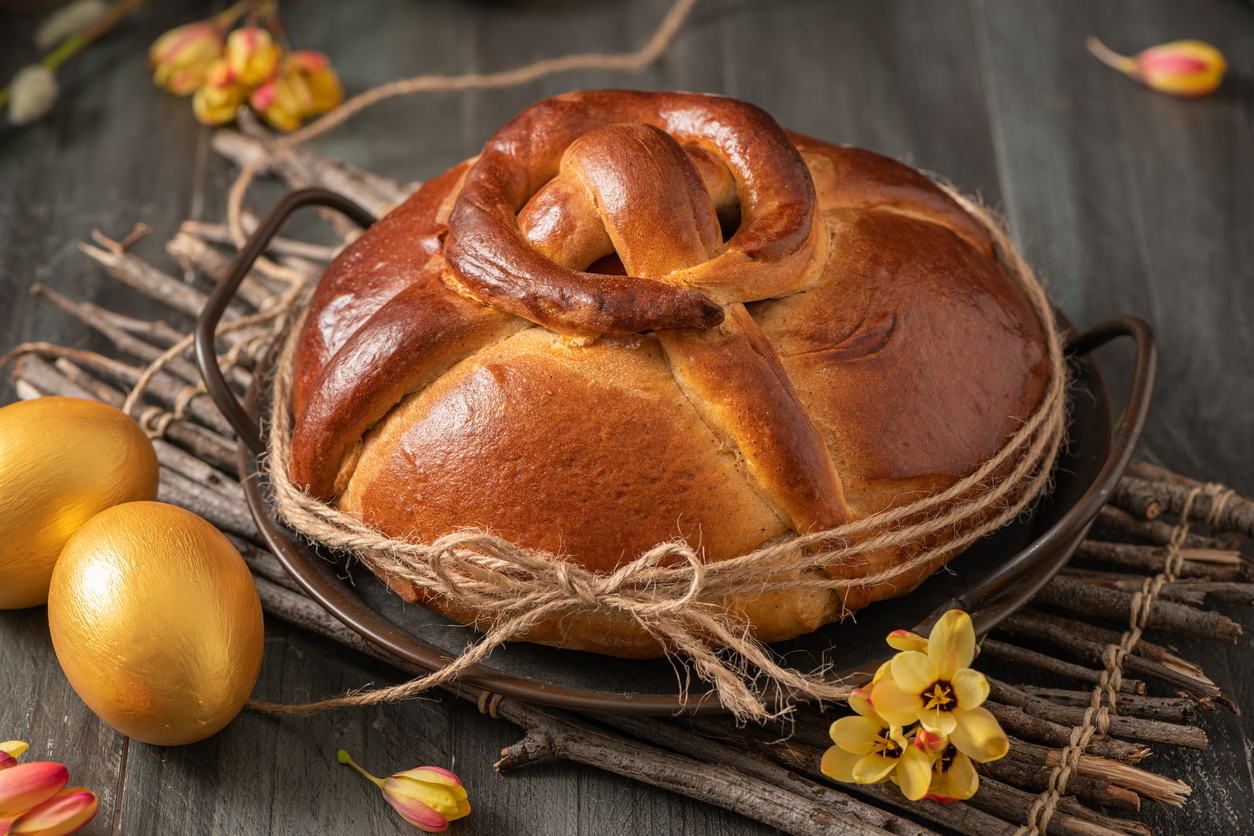 Portuguese traditional Easter cake. Folar with golden eggs on easter table. Blossom flowers and golden painted eggs.