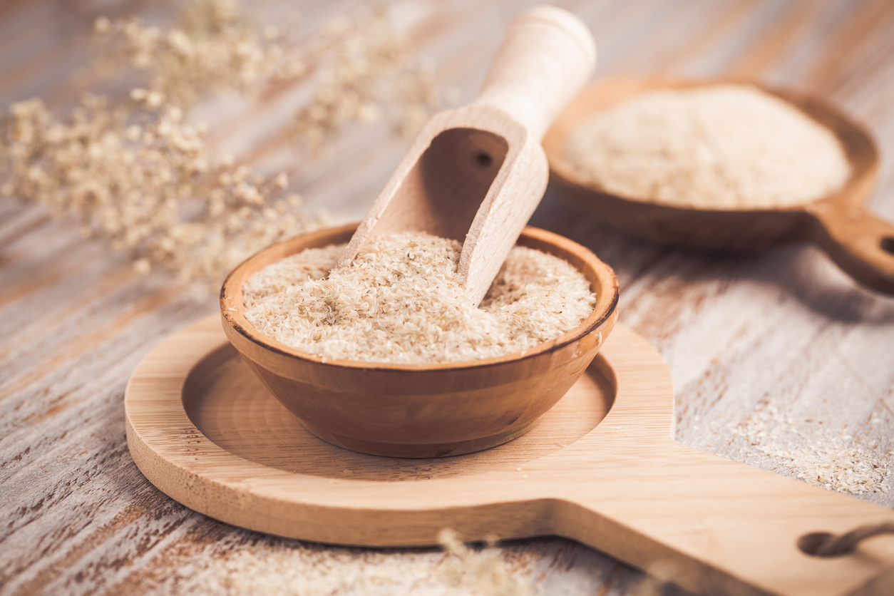 Heap of psyllium husk in wooden bowl on wooden table table. Psyllium husk also called isabgol is fiber derived from the seeds of Plantago ovata plant found in India.